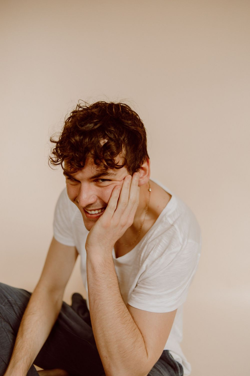 Candid laughing moment captured against warm-toned studio background.