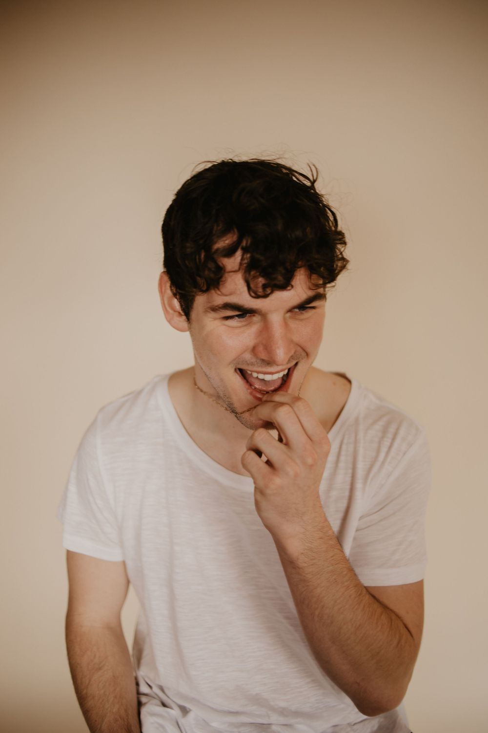Candid laughing portrait against neutral background with warm tones.