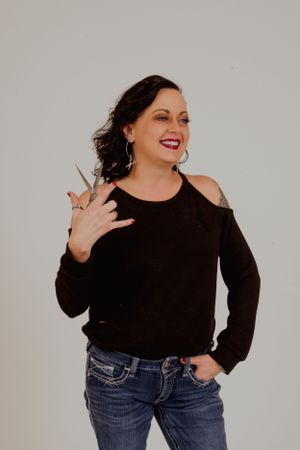 Person in black top and jeans shows playful attitude in studio setting.