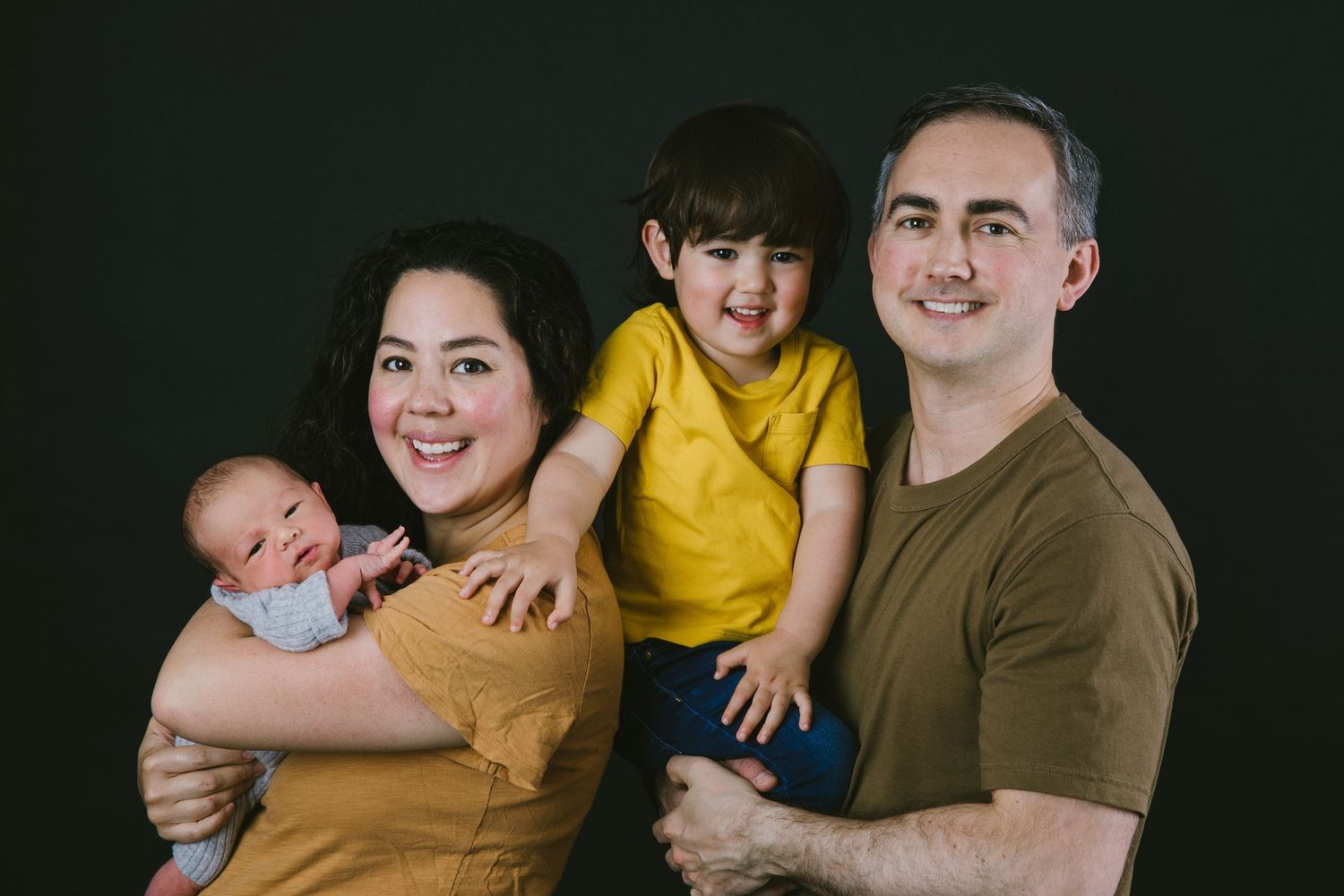 Studio family portrait with parents and children against dark background, in Stoke Newington studio.
