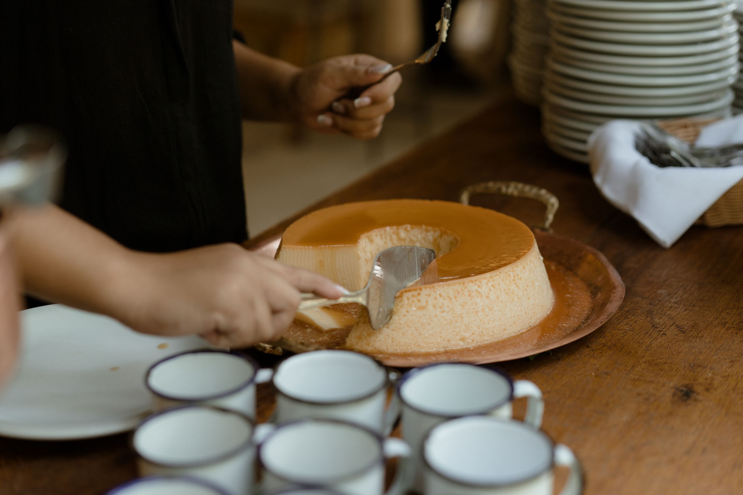 White plates and cups arranged on wooden table for dining service.