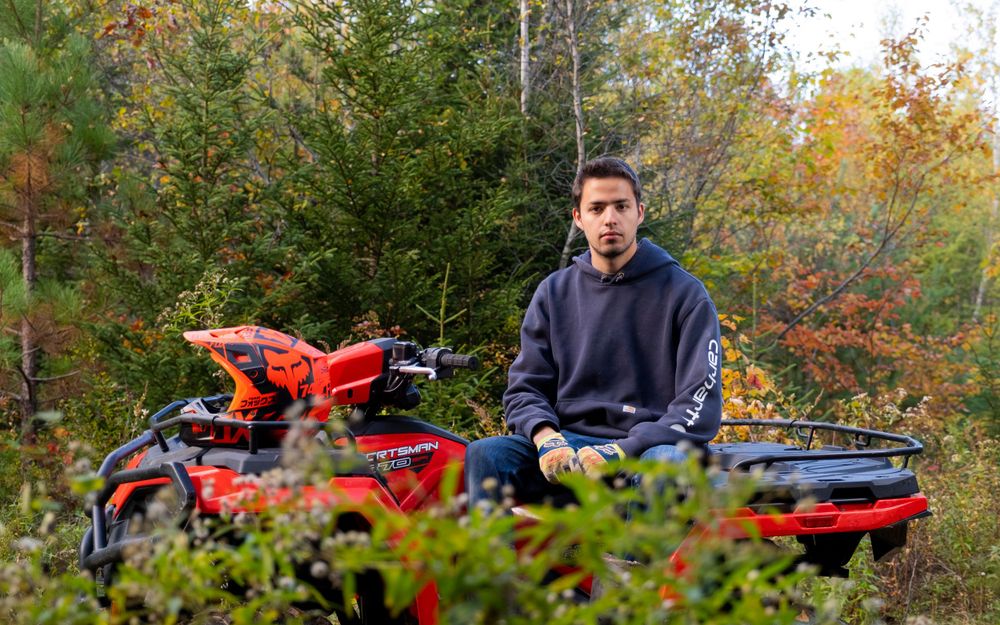 man sitting on atv in woods
