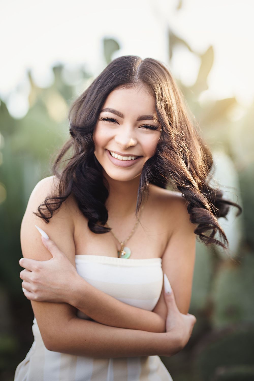 Portrait of someone in white dress smiling outdoors with soft natural lighting.