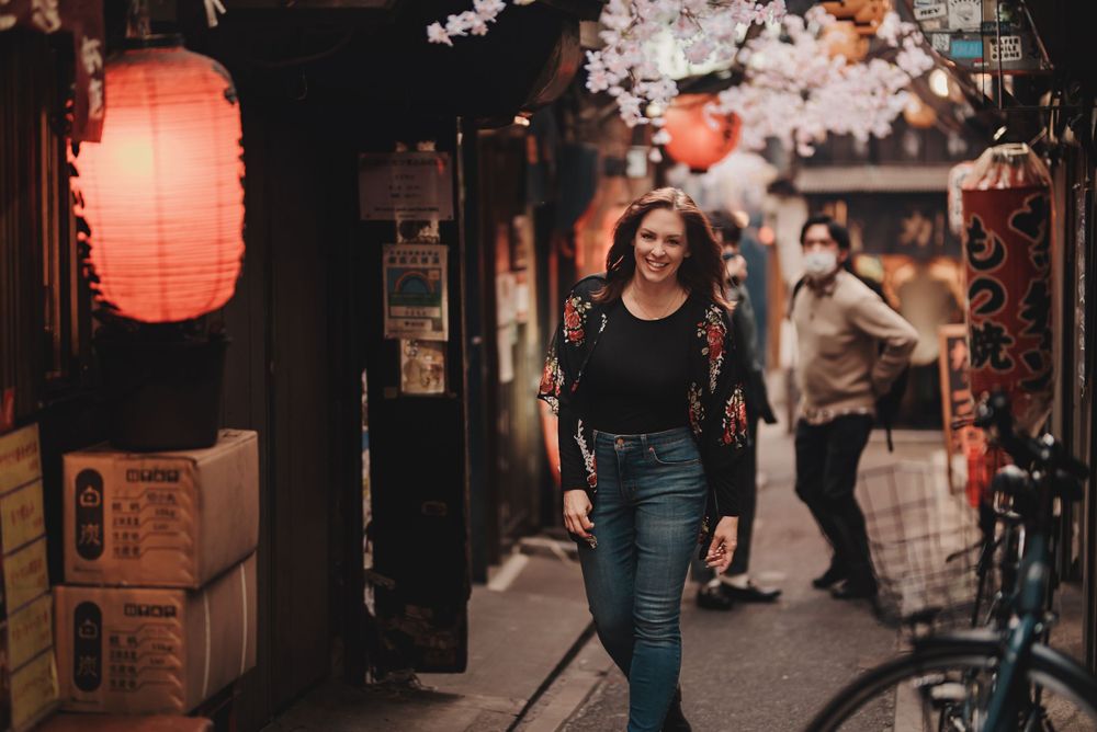 Woman strolling through traditional Japanese street with lanterns and storefronts.