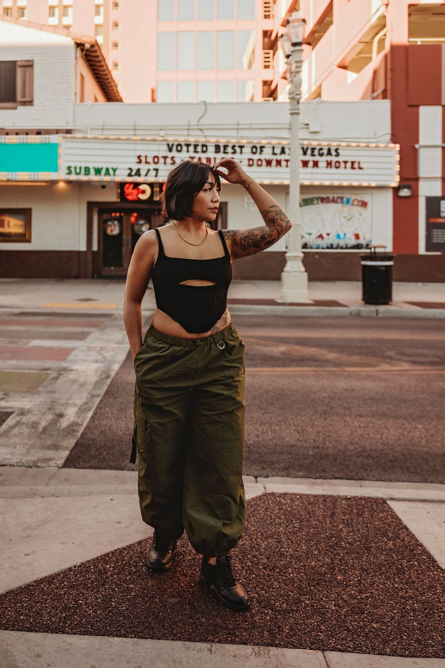 Fashion model poses on a Las Vegas street at sunset wearing urban streetwear with cargo pants and crop top.