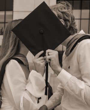Black and white photo of graduates holding their mortarboards.