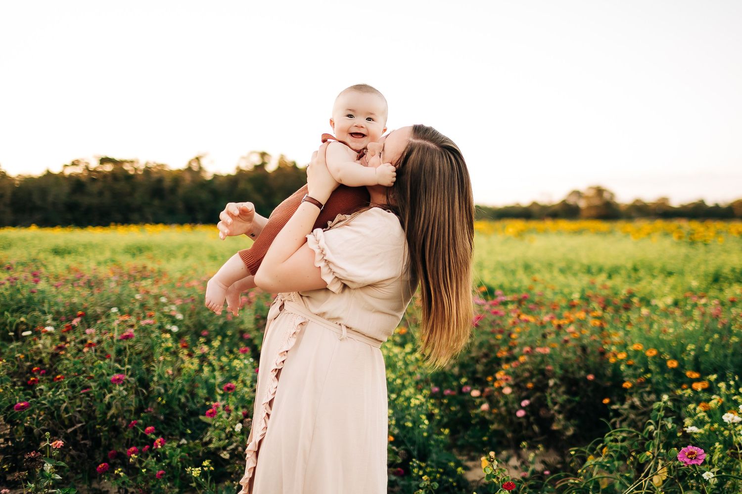 A mother and young child share joyful moments together in a sunlit wildflower field at golden hour in Milton Florida