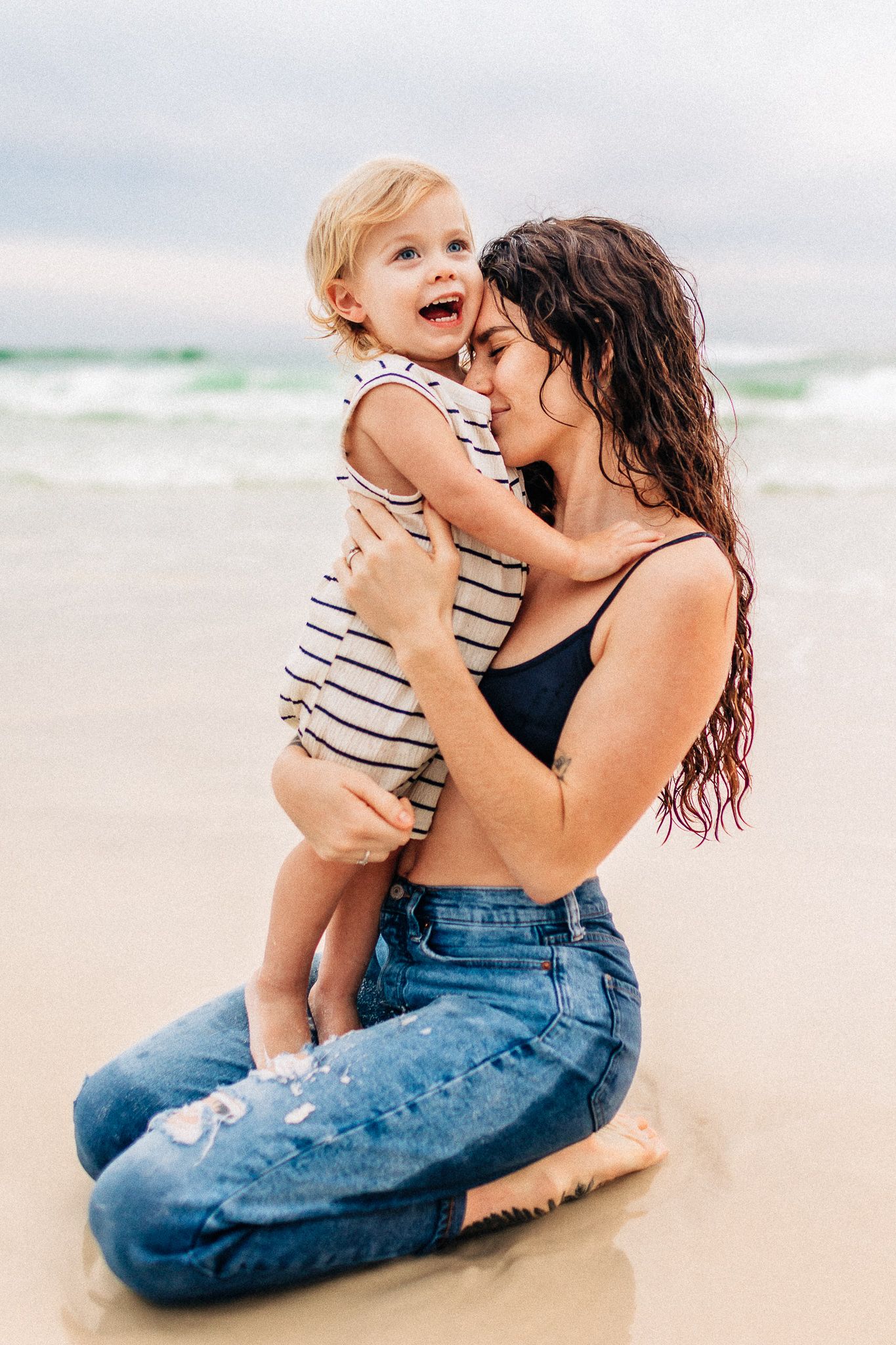 A parent and child share tender moments sitting together on a sandy beach at sunset destin Florida