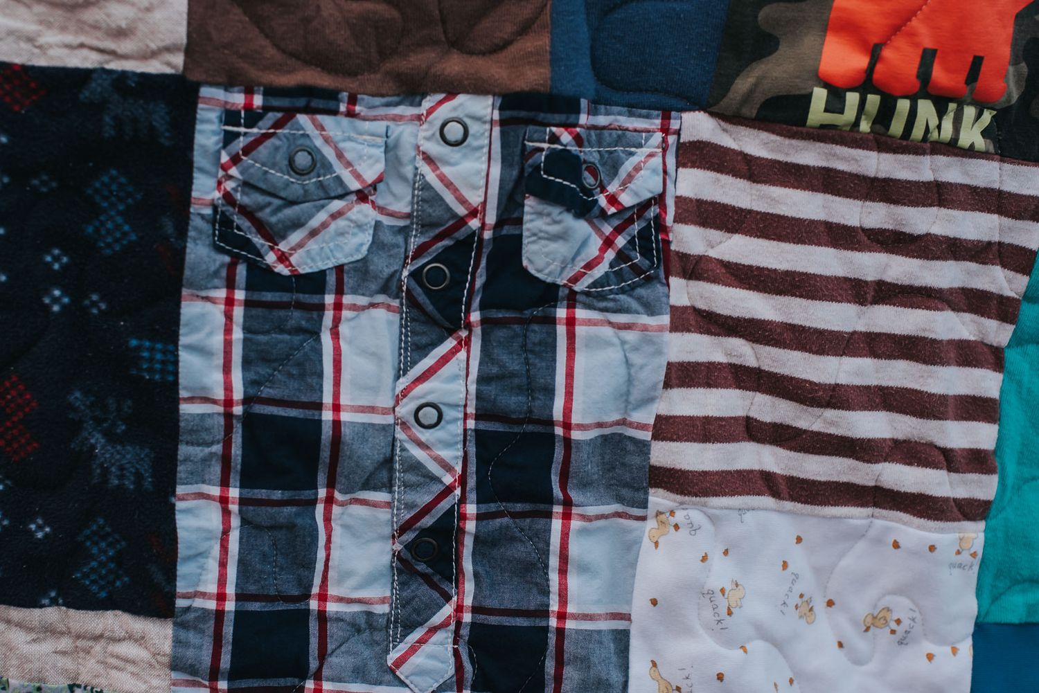 Blue and red checkered child's snap up shirt is featured as a square in a patchwork memory quilt.