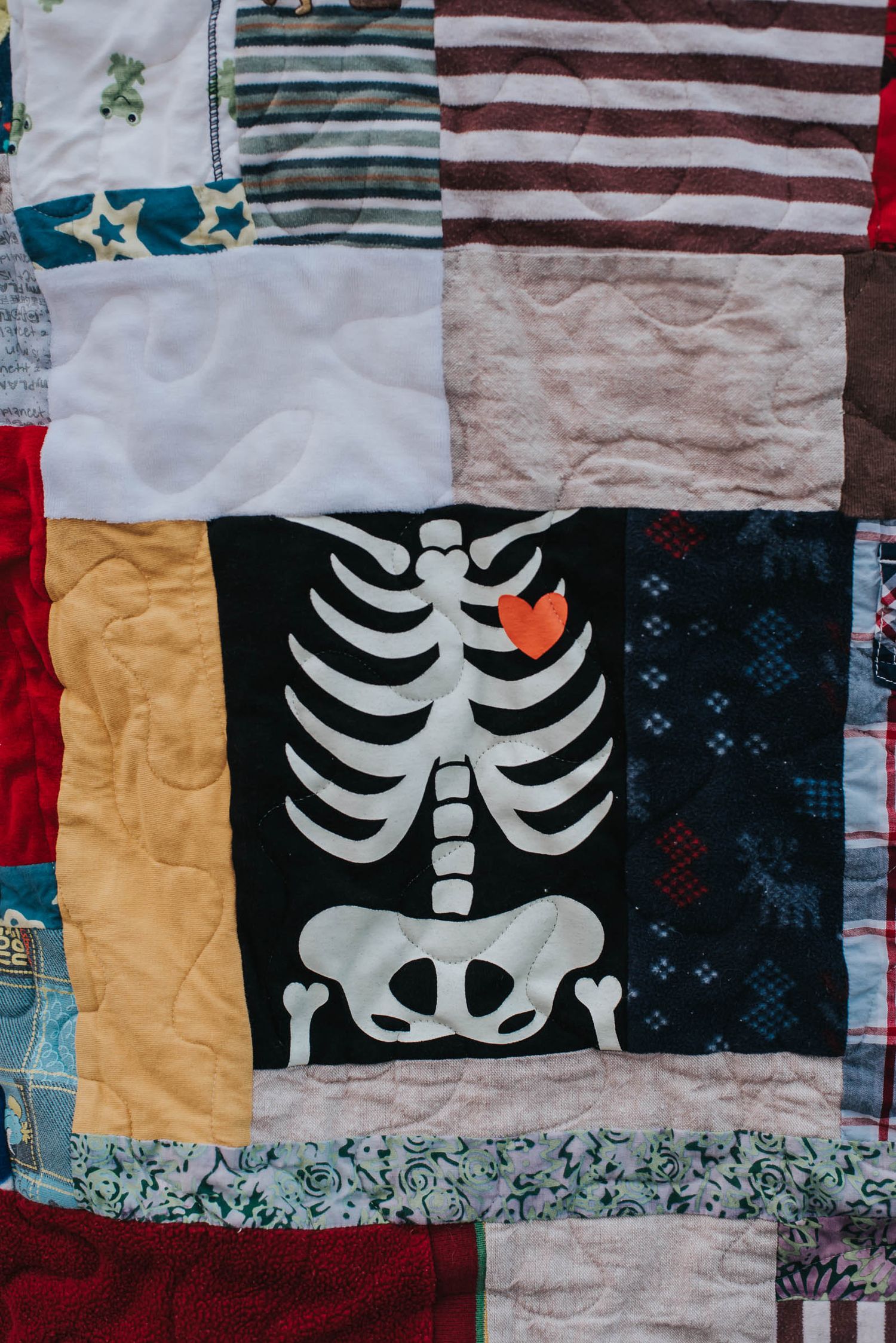 Adorable skeleton shirt with a red heart behind ribs is sewn into a patchwork memory quilt.