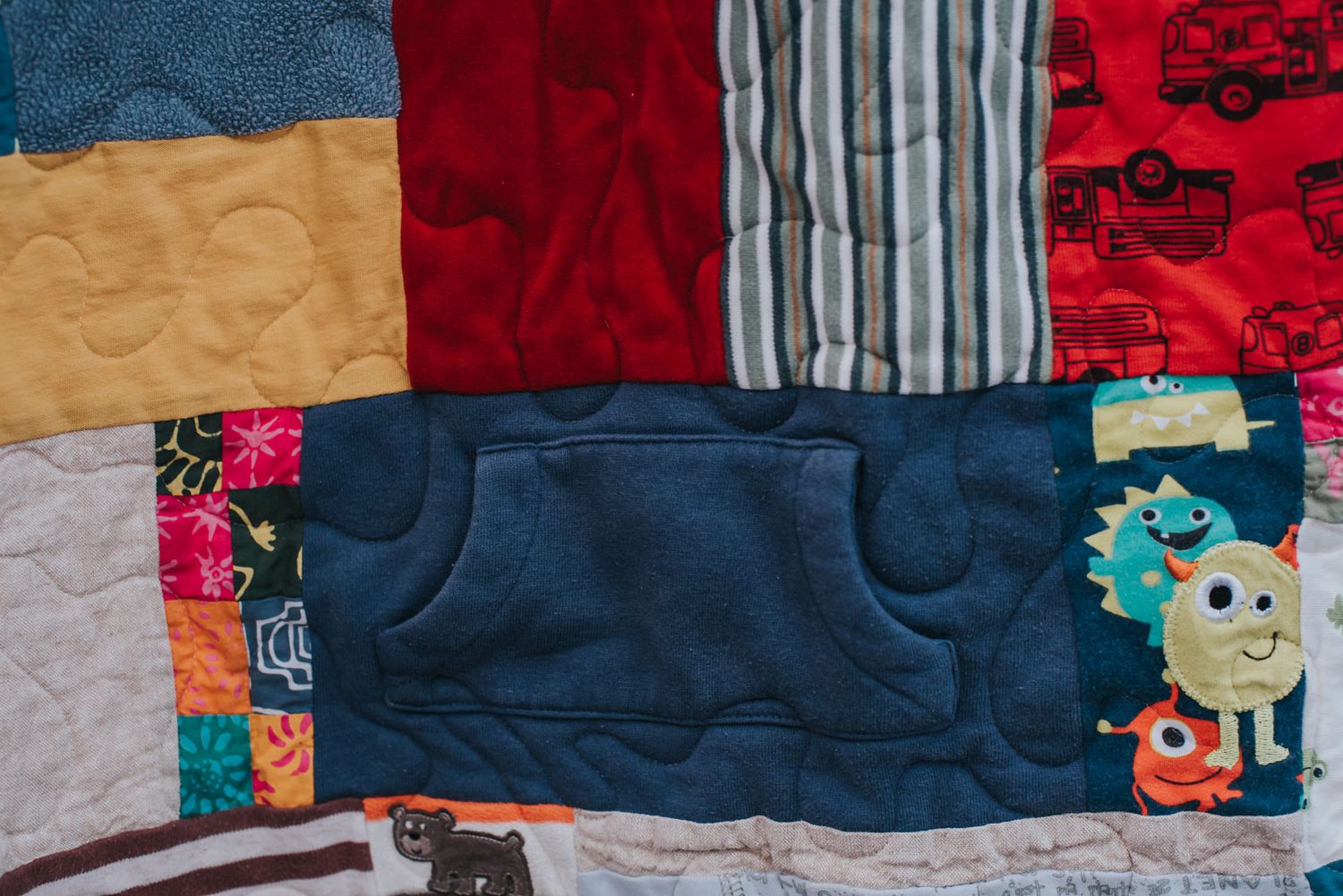 Patchwork featuring a front pocket from a hoodie in a memory quilt made from clothes.