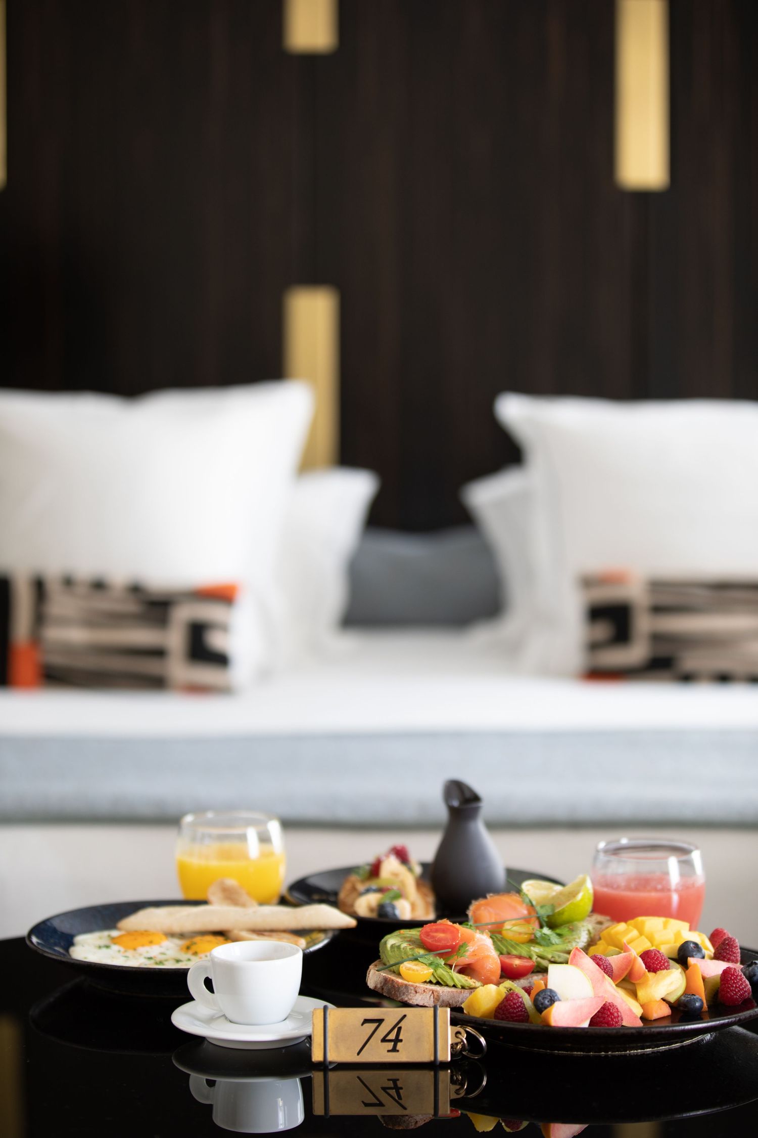 Luxurious breakfast spread with fresh fruit platter and beverages on dark table with table number.
