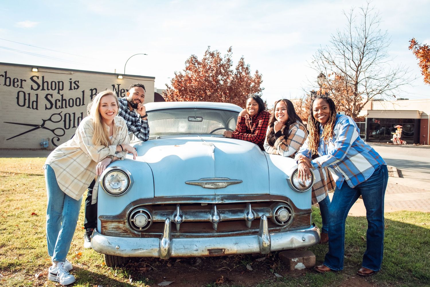 Group photo of coworkers next to a rustic car