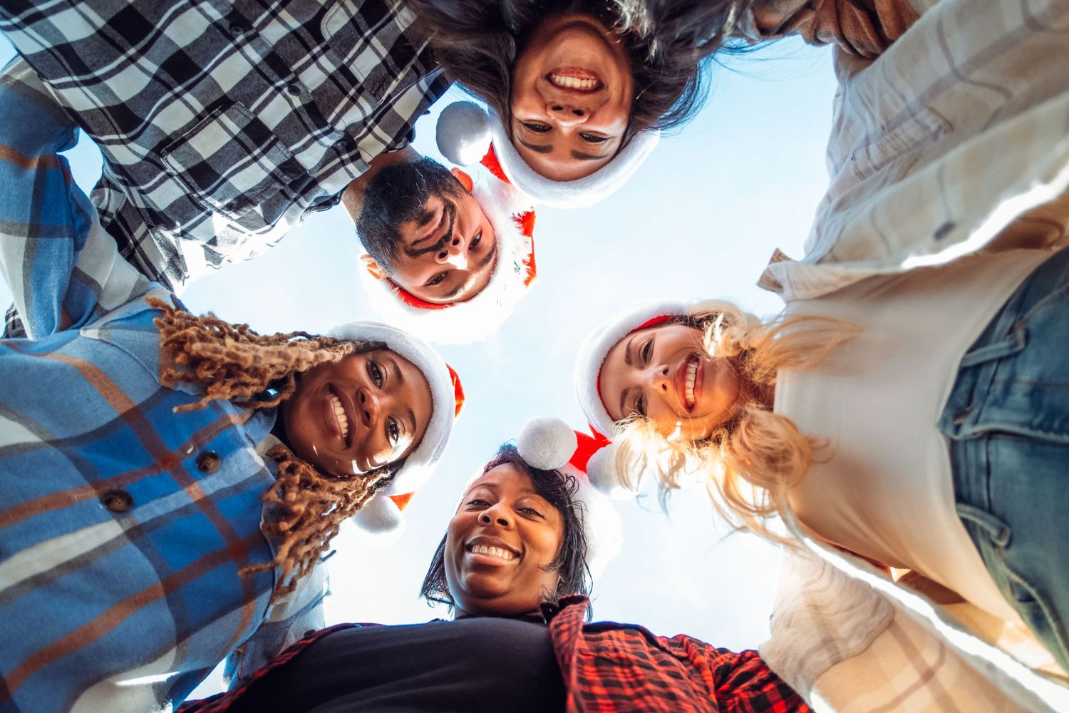 Coworker group photo looking down to the center holding each other in their arms