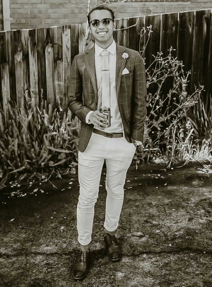 Black and white photo of person in suit and sunglasses at outdoor event.