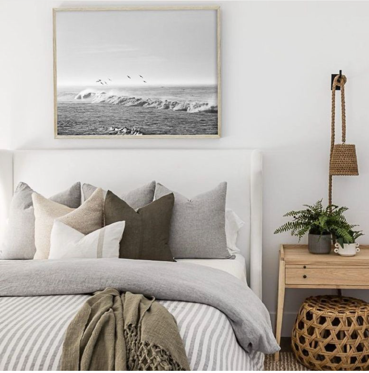 Coastal-themed bedroom with ocean wave artwork and neutral bedding decor.