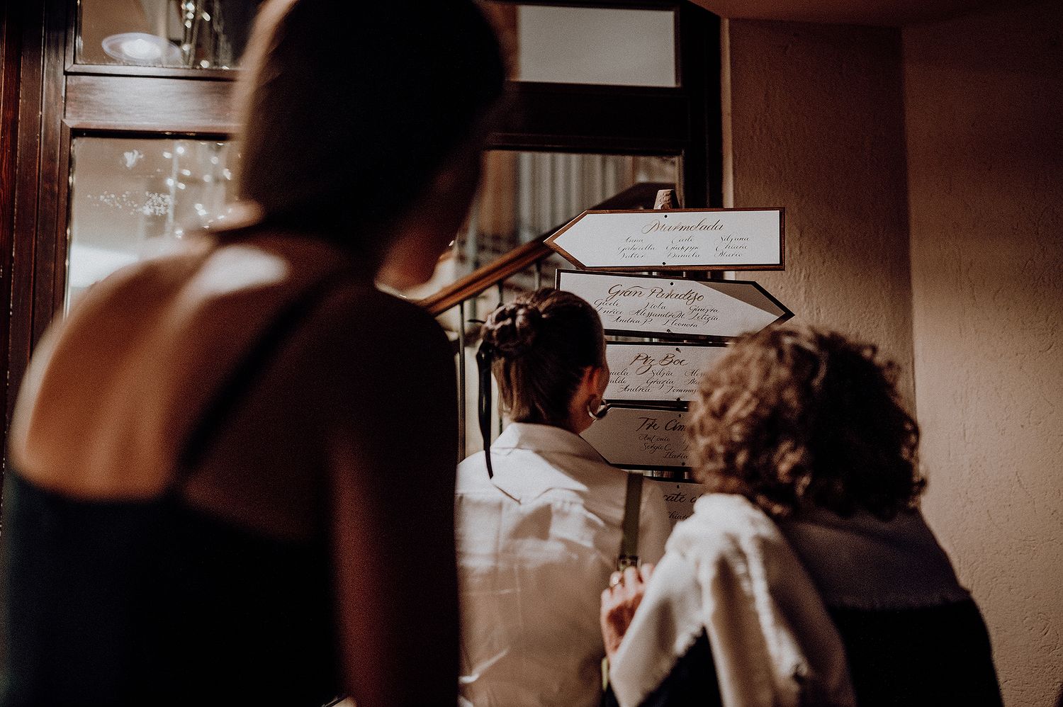 Guests reviewing a wedding menu board in a warmly lit venue.