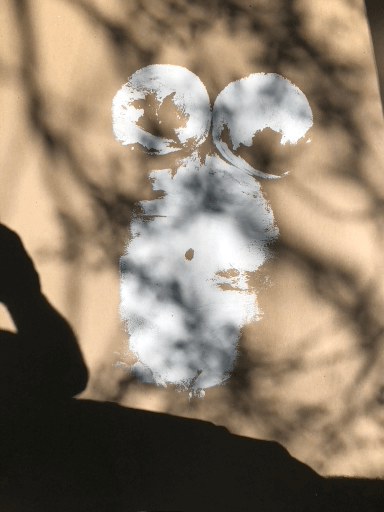 Mickey Mouse shaped snow formation with shadows cast on a beige surface.