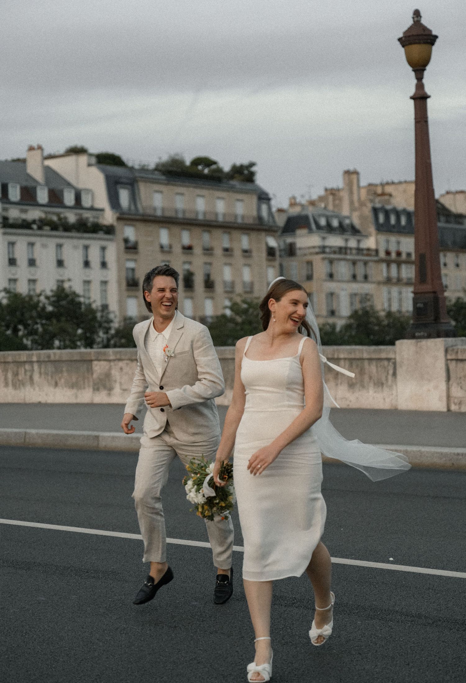 Wedding couple walking along a romantic Parisian street with historic buildings in the background.
