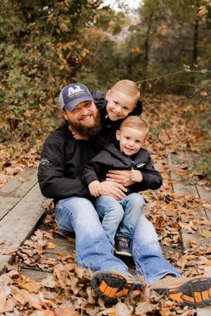 Playful father-son portraits among fallen autumn leaves on wooden steps.