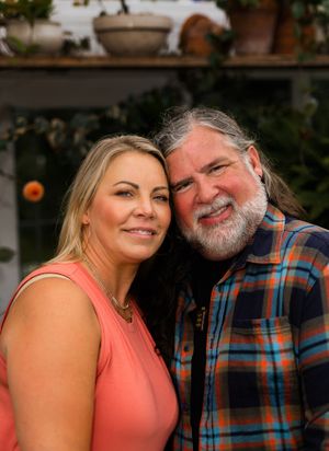 Intimate couple portraits with coral top and plaid shirt against natural background.