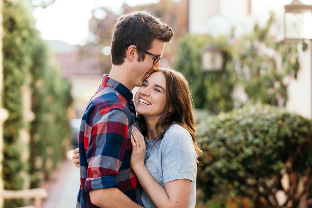 Tender moment shared between couple on urban street with garden backdrop.