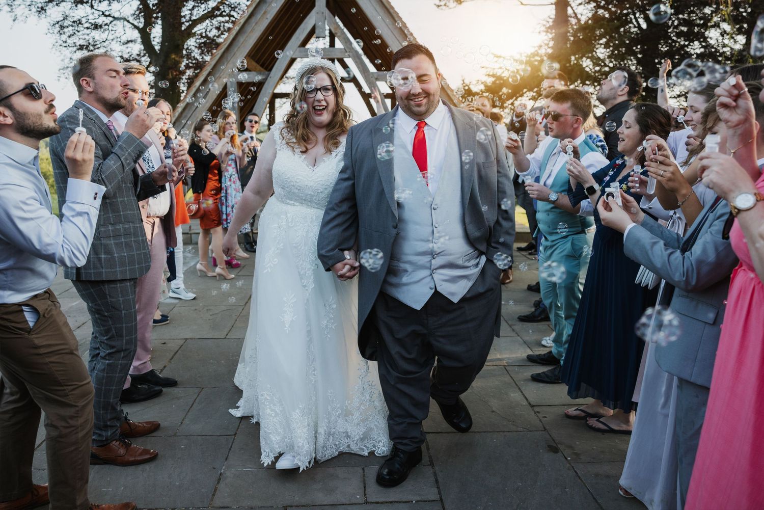 Emily and Dan walking in an aisle of their friends blowing bubbles at them