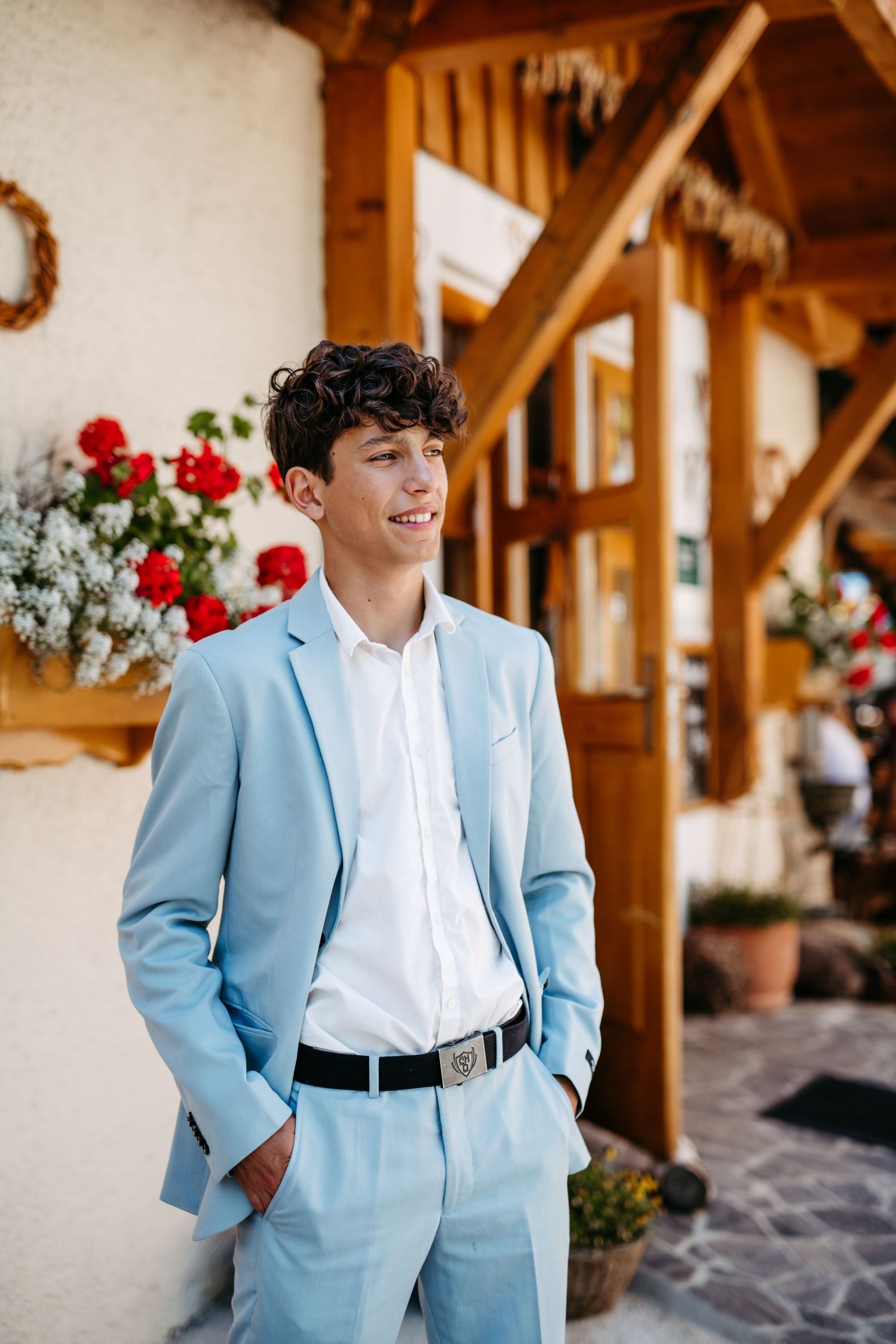 Formal portrait of someone in a light blue suit and white shirt against a floral backdrop.