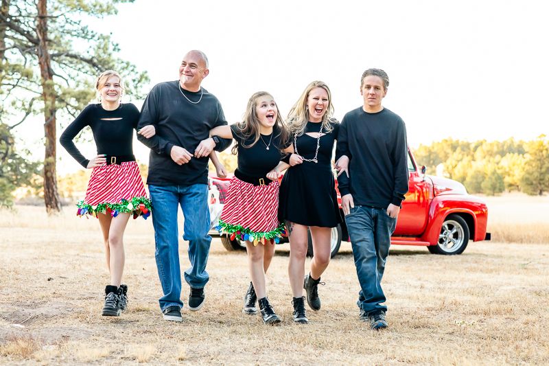 Family with three teens goof off together in front of a vintage red truck in Colorado Springs, Colorado.