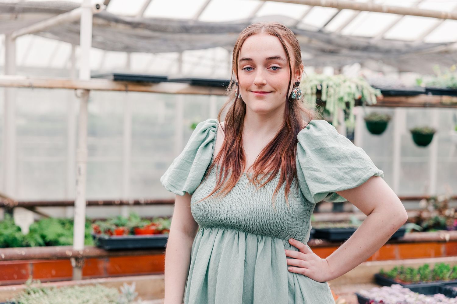 Full length portrait in greenhouse wearing mint green smocked dress with puff sleeves.