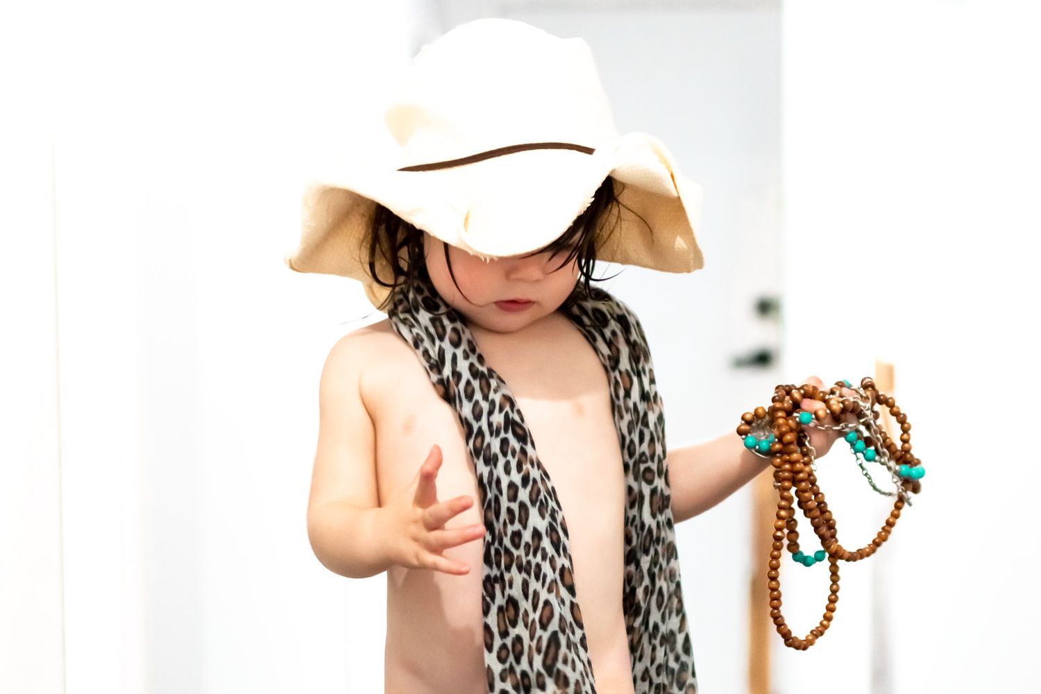 Toddler dressed up with hat scarf and beads