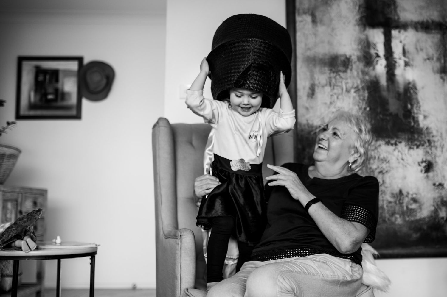 Nan and young girl playing together fun image with basket on girls head