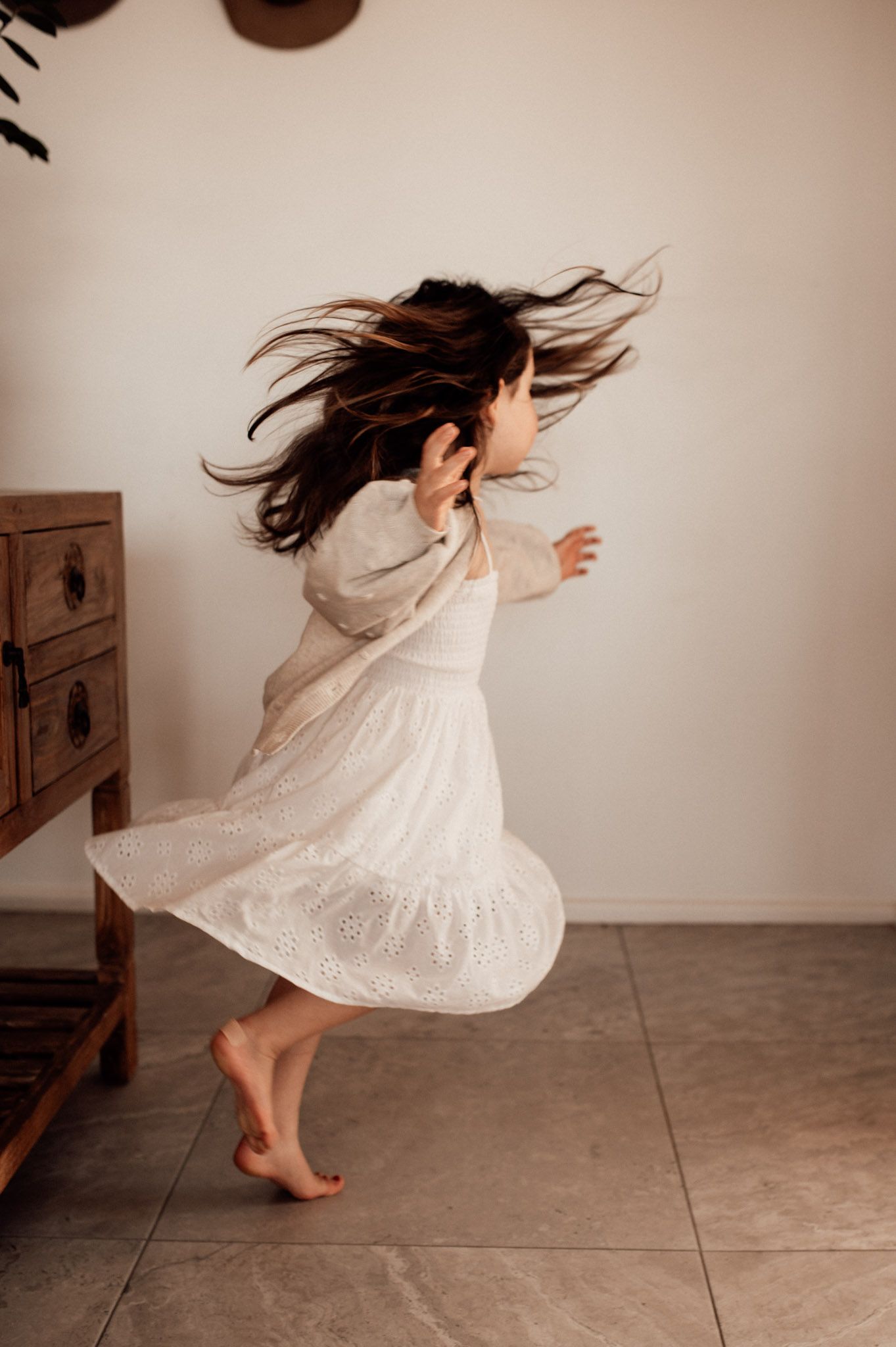 Young girl dancing, twirling in white dress