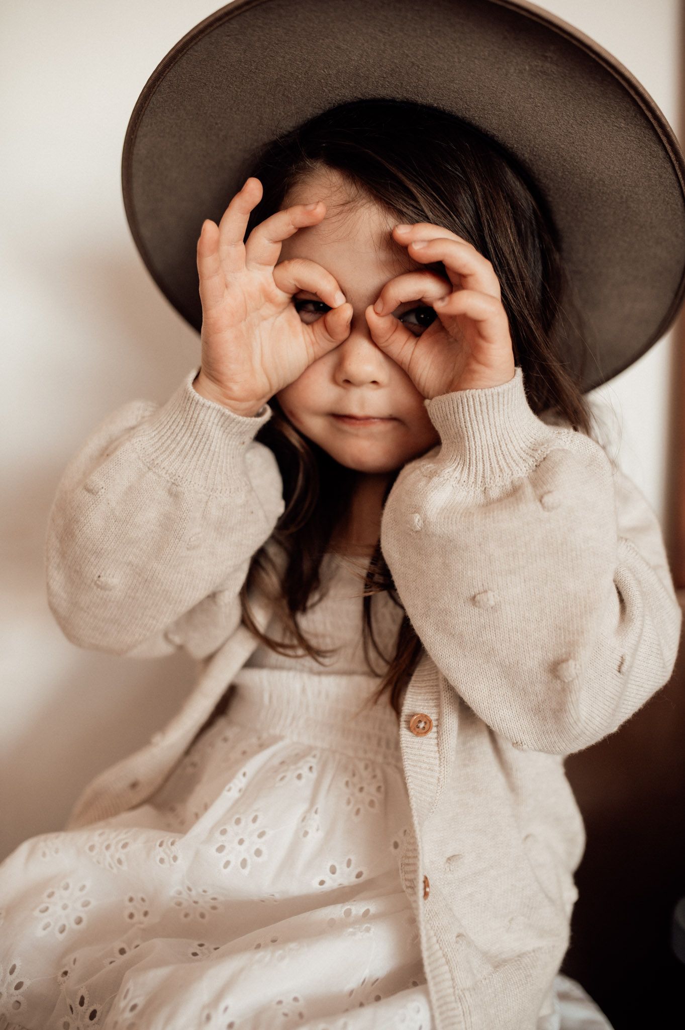 Girl holding hands up to eyes in cowboy hat