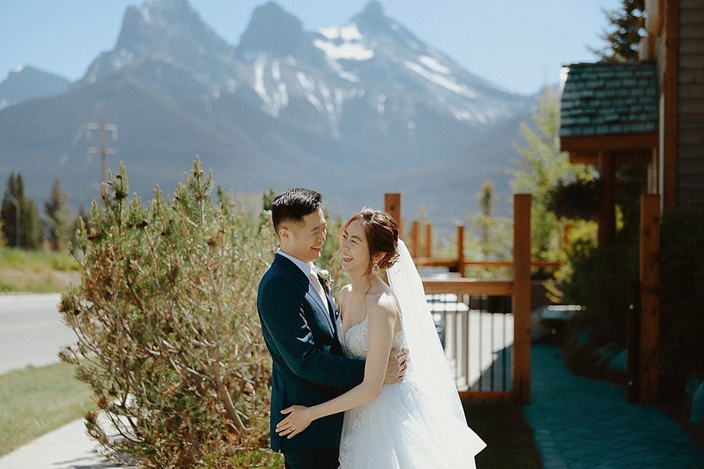 A romantic wedding moment captured with snow-capped mountains and evergreen trees in the background.