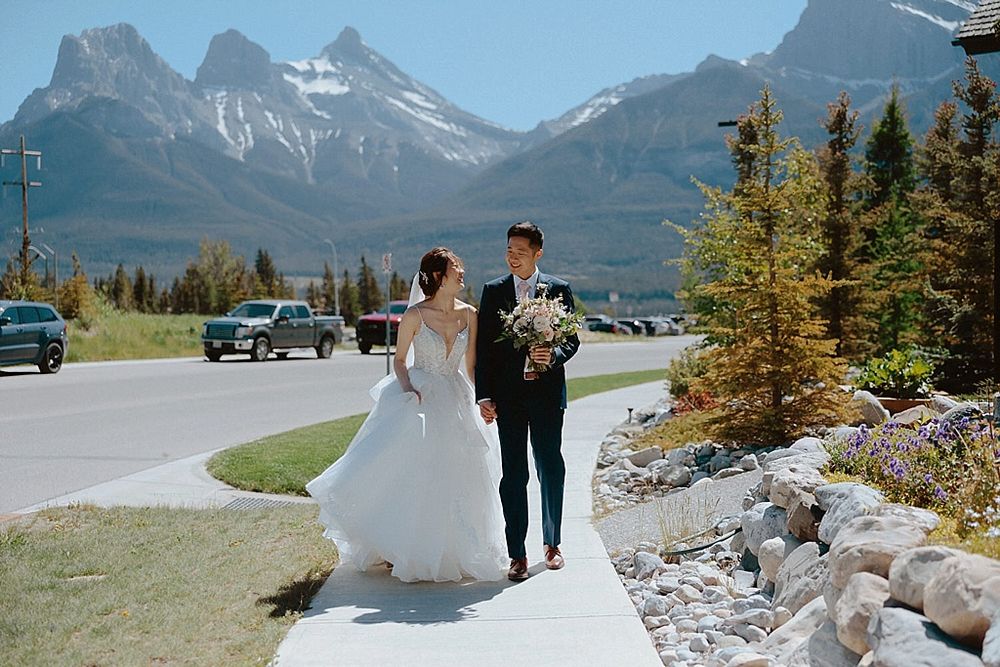 A couple strolls along a pathway with towering mountain peaks creating a stunning backdrop.