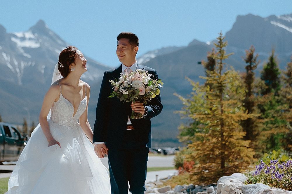 A joyful wedding portrait with dramatic mountain scenery and vibrant blue skies.