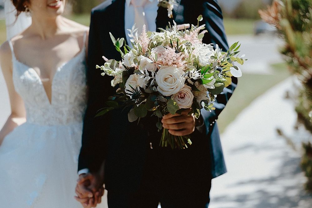 An elegant white and blush wedding bouquet held against formal wedding attire.
