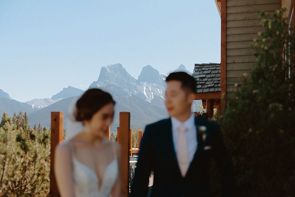 A romantic wedding portrait against a backdrop of majestic mountain peaks and blue skies.