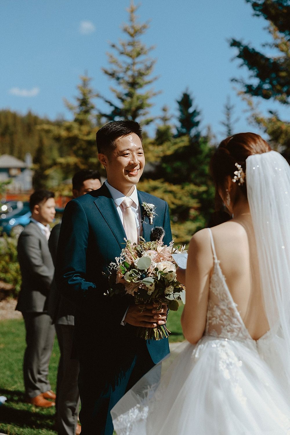Joyful wedding moment captured in sunny outdoor setting with pine trees.