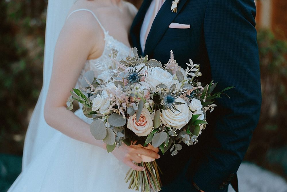 Elegant white and blush wedding bouquet with roses and greenery.