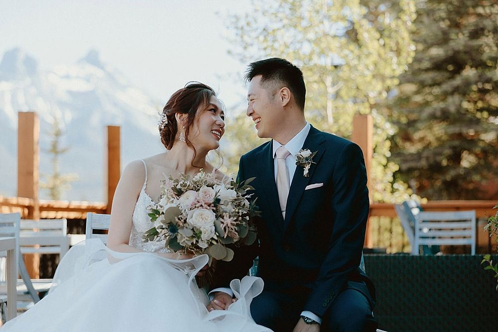 Elegant outdoor wedding ceremony with snowy mountain peaks and evergreen trees in the background.