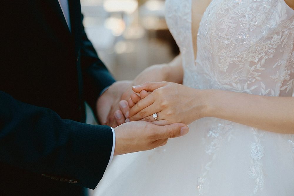 Close-up of hands holding during intimate wedding ceremony moment.