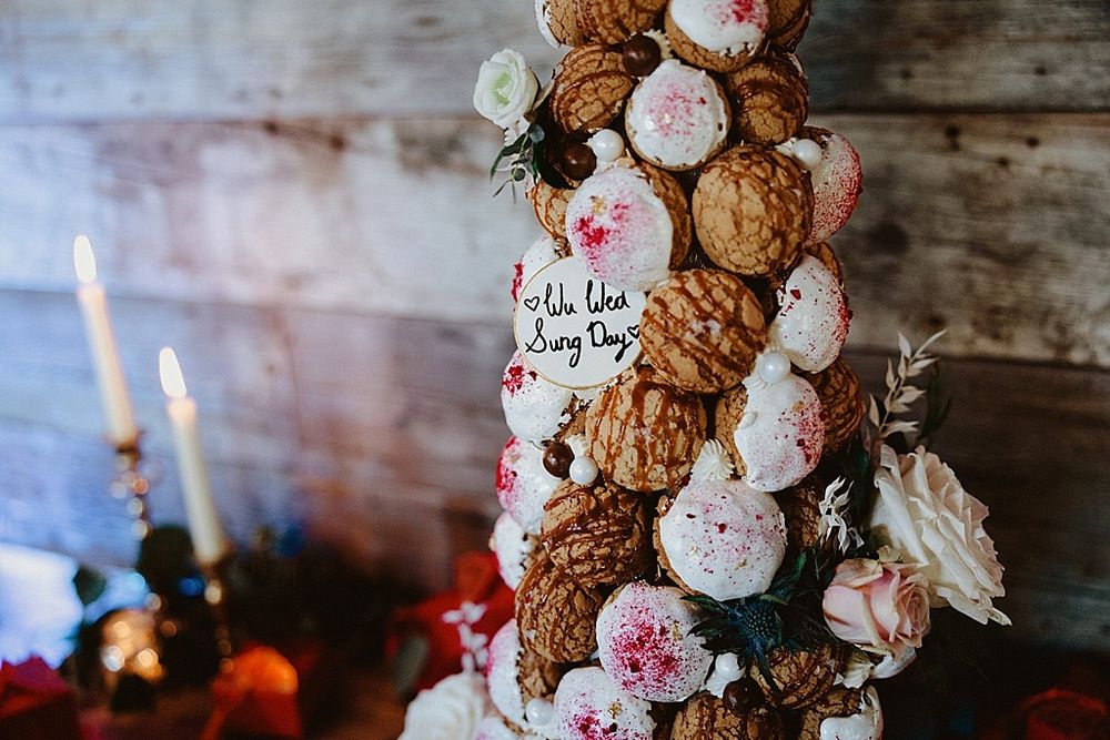 Ornate wedding cake display with floral decorations against rustic wooden background.