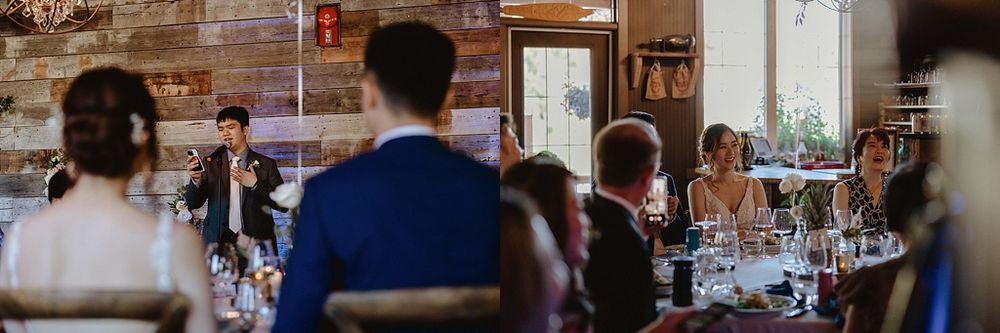 Wedding reception guests mingle and dine in an elegant rustic venue with wooden walls and crystal chandeliers.
