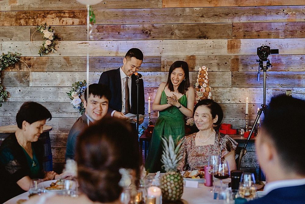 Lively wedding reception dinner scene with guests dining at long tables decorated with pineapples.