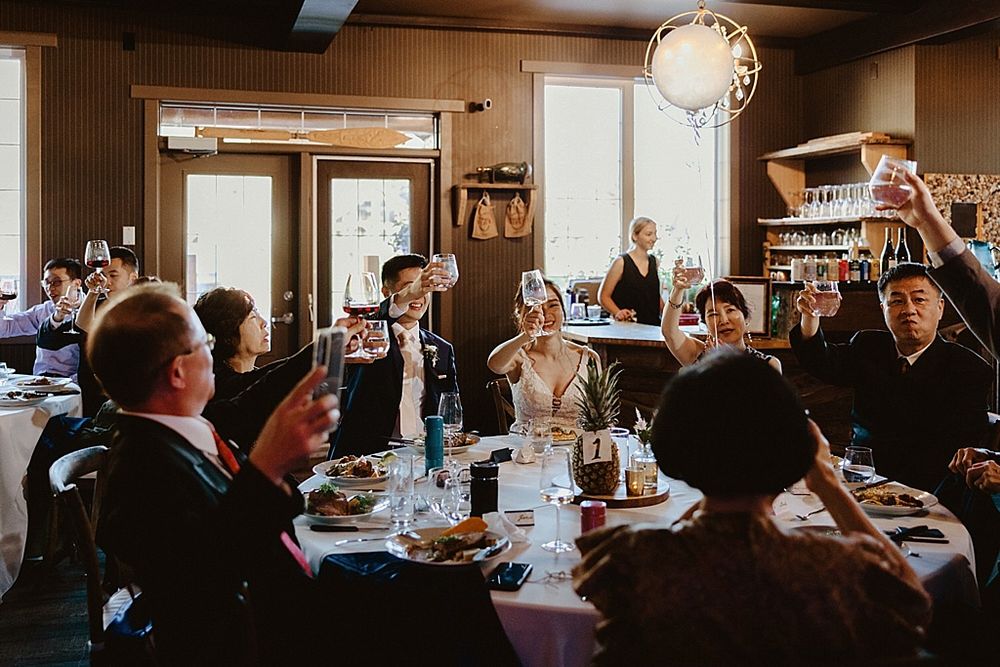 Panoramic view of wedding reception dinner in a cozy restaurant with exposed wood beams.