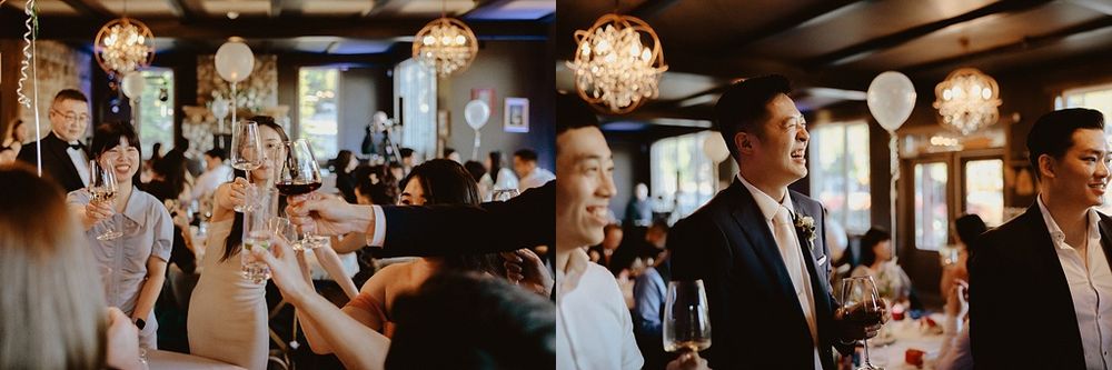 Wedding reception panorama showing guests dining under crystal chandeliers in rustic setting.