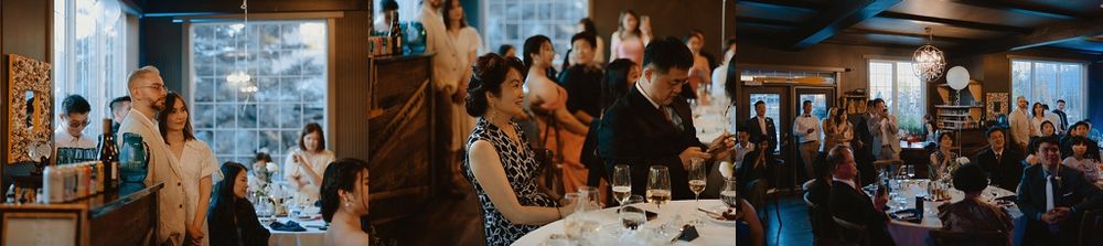 Wide angle shot of wedding reception space with exposed brick walls and crystal chandeliers.