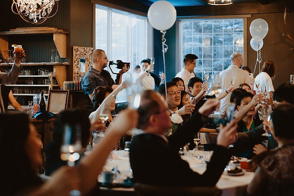 Wedding guests raising their hands in celebration under crystal chandeliers.